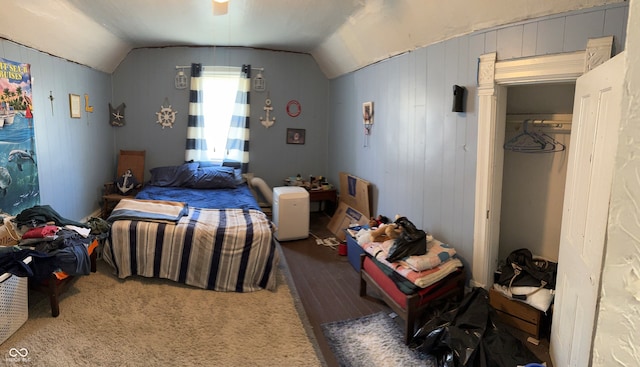 bedroom featuring ceiling fan, hardwood / wood-style flooring, vaulted ceiling, and wood walls