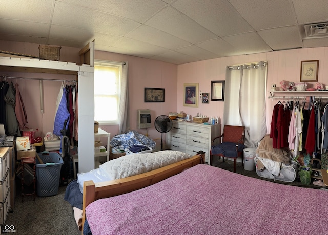 bedroom with a closet, a paneled ceiling, heating unit, and carpet