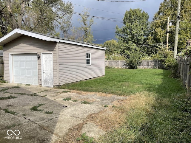 detached garage with concrete driveway and fence