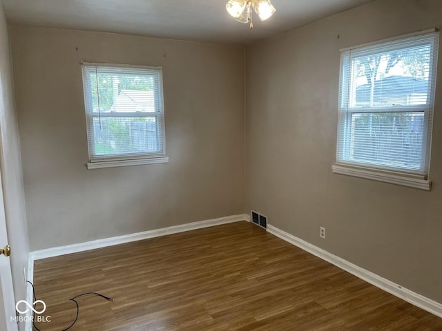 spare room featuring baseboards, ceiling fan, visible vents, and wood finished floors