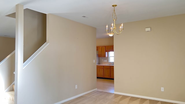 empty room with a chandelier, light colored carpet, and sink