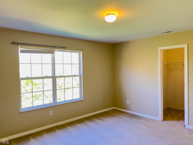 unfurnished bedroom with a closet, a spacious closet, and light colored carpet