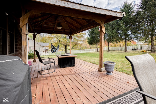 wooden terrace featuring area for grilling, a gazebo, an outdoor fire pit, ceiling fan, and a lawn