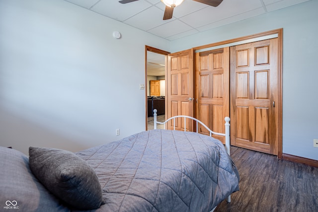 bedroom with a closet, ceiling fan, a drop ceiling, and dark hardwood / wood-style floors