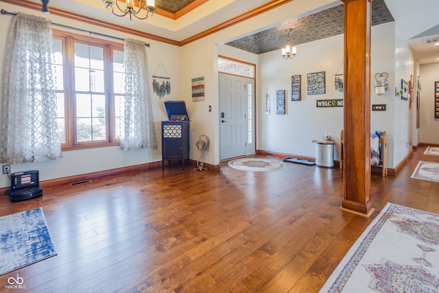 entrance foyer with dark wood-type flooring, crown molding, and a notable chandelier