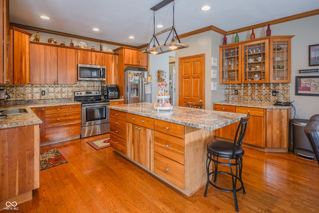 kitchen with a kitchen island, light hardwood / wood-style flooring, stainless steel appliances, pendant lighting, and tasteful backsplash