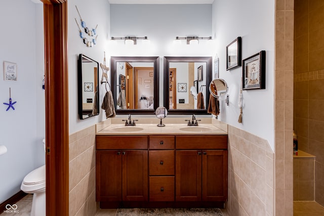 bathroom featuring vanity, toilet, tile walls, and a tile shower