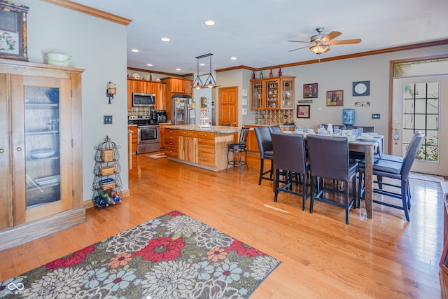 dining room with ornamental molding, light hardwood / wood-style flooring, and ceiling fan