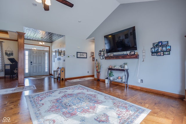 foyer with high vaulted ceiling, decorative columns, wood-type flooring, and ceiling fan with notable chandelier