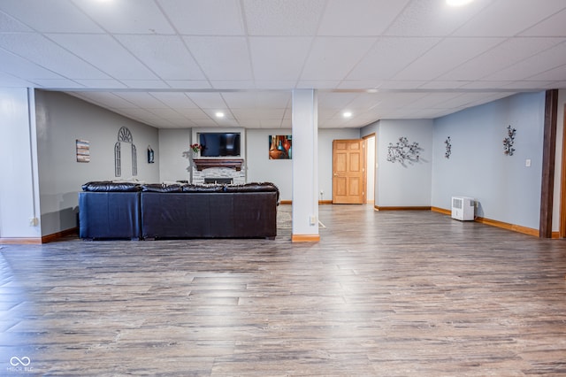 unfurnished living room featuring a drop ceiling, hardwood / wood-style floors, and a fireplace