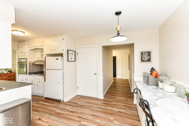 kitchen with decorative backsplash, white cabinets, pendant lighting, light wood-type flooring, and appliances with stainless steel finishes