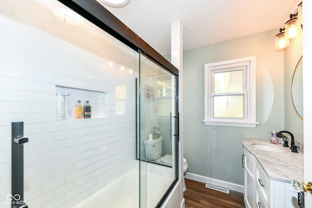 full bathroom featuring vanity, toilet, hardwood / wood-style flooring, and enclosed tub / shower combo