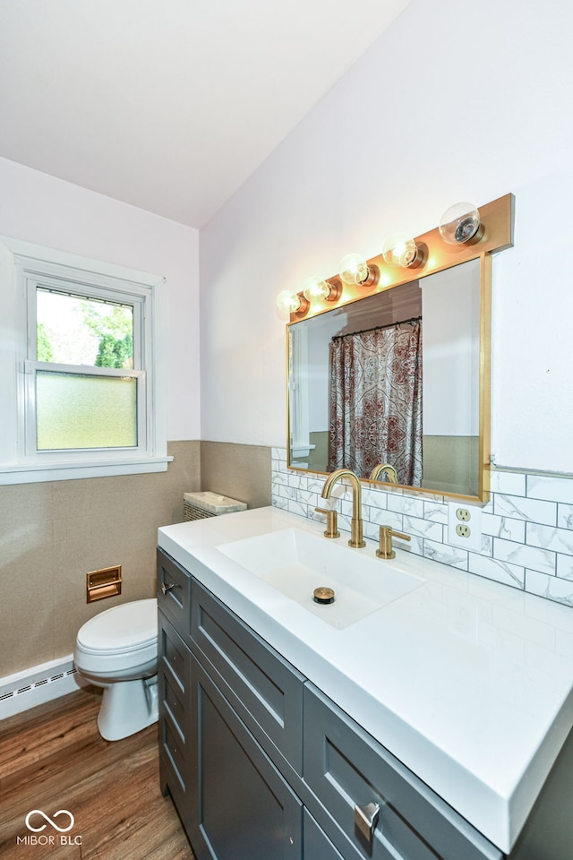 bathroom with hardwood / wood-style flooring, toilet, baseboard heating, tile walls, and vanity