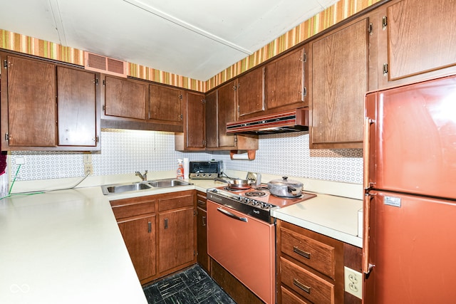 kitchen featuring custom range hood, refrigerator, range, and sink