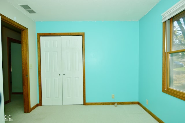 unfurnished bedroom with light colored carpet and a closet