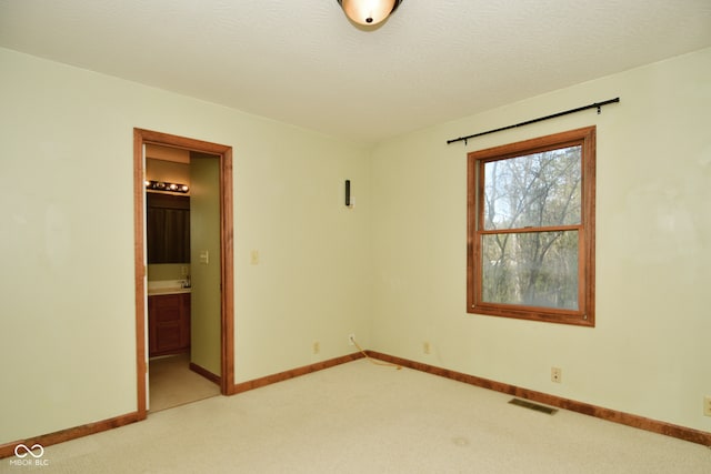 empty room with a textured ceiling and light carpet