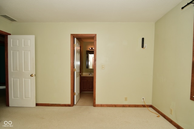 empty room featuring a textured ceiling, light carpet, and sink