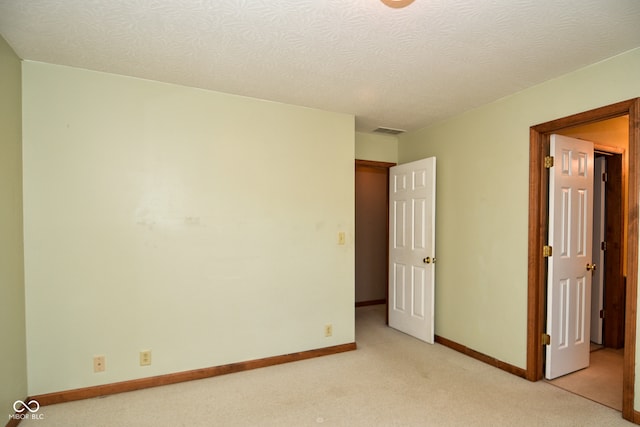 carpeted empty room featuring a textured ceiling