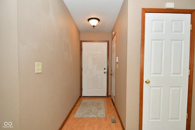 hallway with a textured ceiling and light hardwood / wood-style flooring