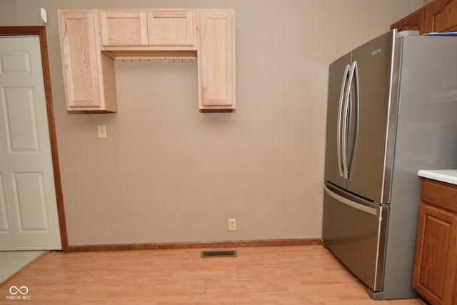 kitchen featuring stainless steel refrigerator and light hardwood / wood-style floors