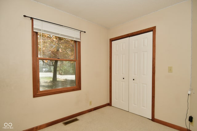 unfurnished bedroom featuring a closet and light colored carpet