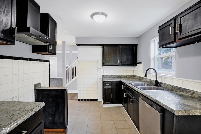 kitchen with dishwasher, wall chimney exhaust hood, sink, light tile patterned floors, and tile walls