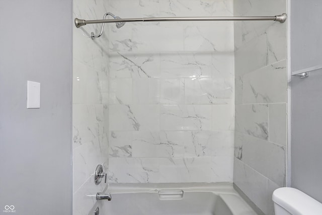 bathroom with toilet and tiled shower / bath