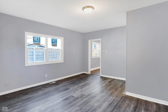 empty room with dark hardwood / wood-style floors and a healthy amount of sunlight