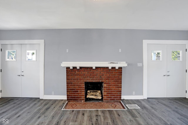 unfurnished living room with french doors, a brick fireplace, and wood-type flooring