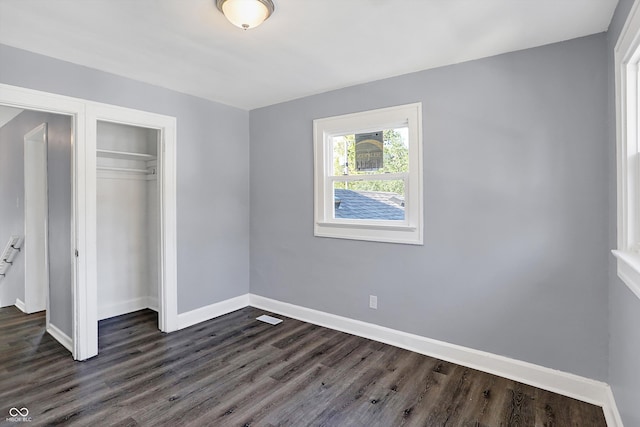 unfurnished bedroom with a closet and dark hardwood / wood-style flooring