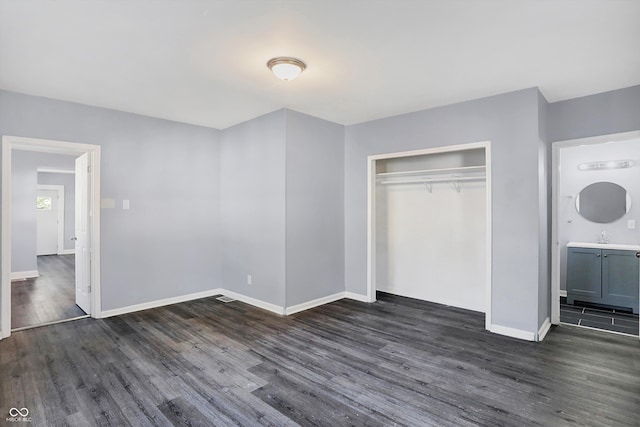 unfurnished bedroom with sink, ensuite bathroom, dark hardwood / wood-style floors, and a closet