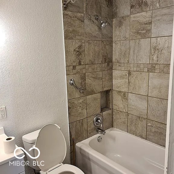 bathroom featuring tiled shower / bath and toilet