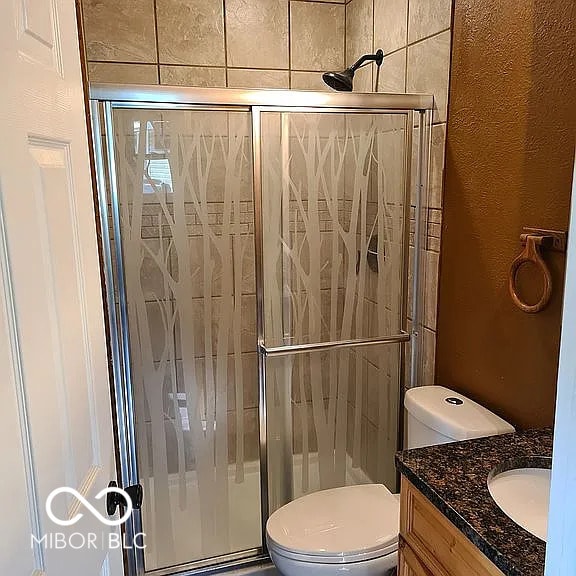 bathroom featuring toilet, walk in shower, and vanity