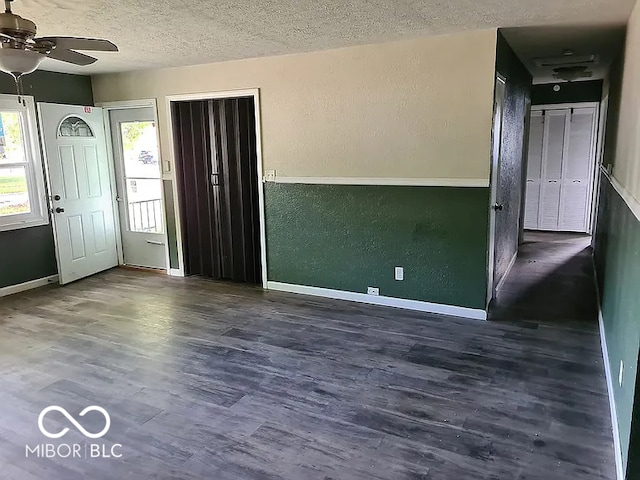 unfurnished room featuring dark wood-type flooring, a textured ceiling, and ceiling fan