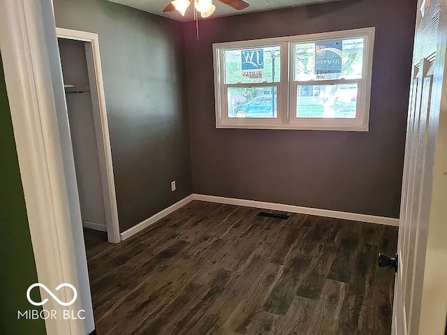 unfurnished bedroom featuring a closet, multiple windows, dark hardwood / wood-style floors, and ceiling fan