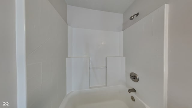 bathroom featuring a textured ceiling and tiled shower / bath