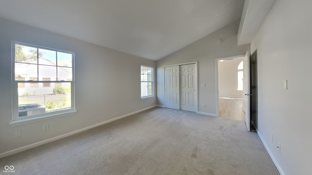 unfurnished bedroom featuring light carpet, vaulted ceiling, and multiple windows