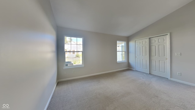 unfurnished bedroom featuring light carpet, lofted ceiling, and a closet