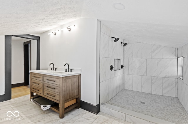 bathroom featuring a tile shower, a textured ceiling, wood-type flooring, and vanity