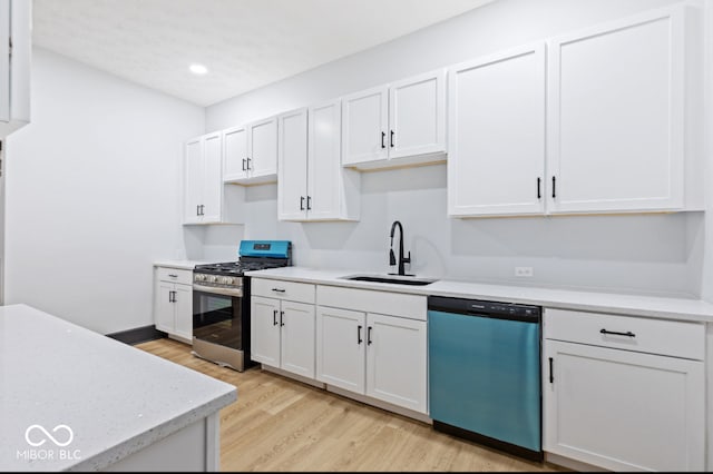 kitchen with sink, appliances with stainless steel finishes, light wood-type flooring, and white cabinets