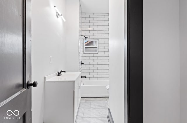 full bathroom featuring vanity, tiled shower / bath combo, and toilet