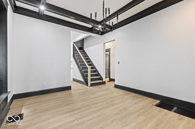 unfurnished living room with an inviting chandelier, light hardwood / wood-style flooring, beam ceiling, and coffered ceiling