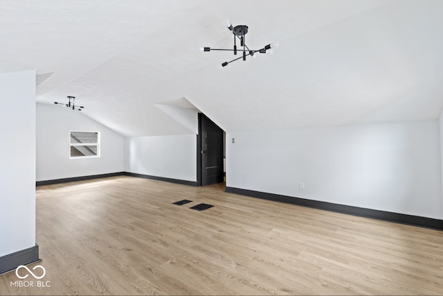 bonus room featuring an inviting chandelier, vaulted ceiling, and light hardwood / wood-style floors