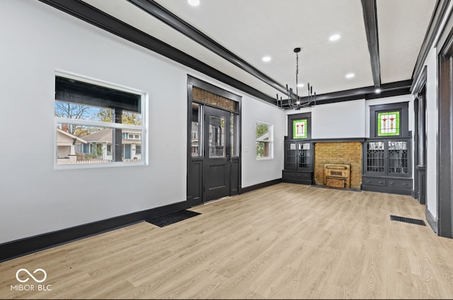 unfurnished living room with beamed ceiling, a notable chandelier, and light hardwood / wood-style floors