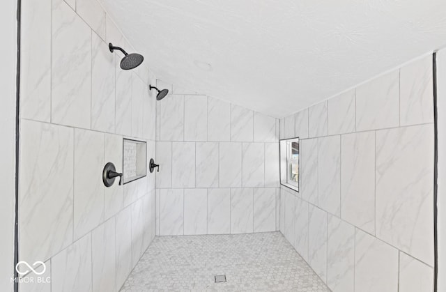 bathroom with a tile shower and a textured ceiling