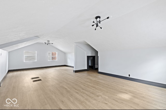 bonus room with vaulted ceiling, light hardwood / wood-style flooring, and a textured ceiling