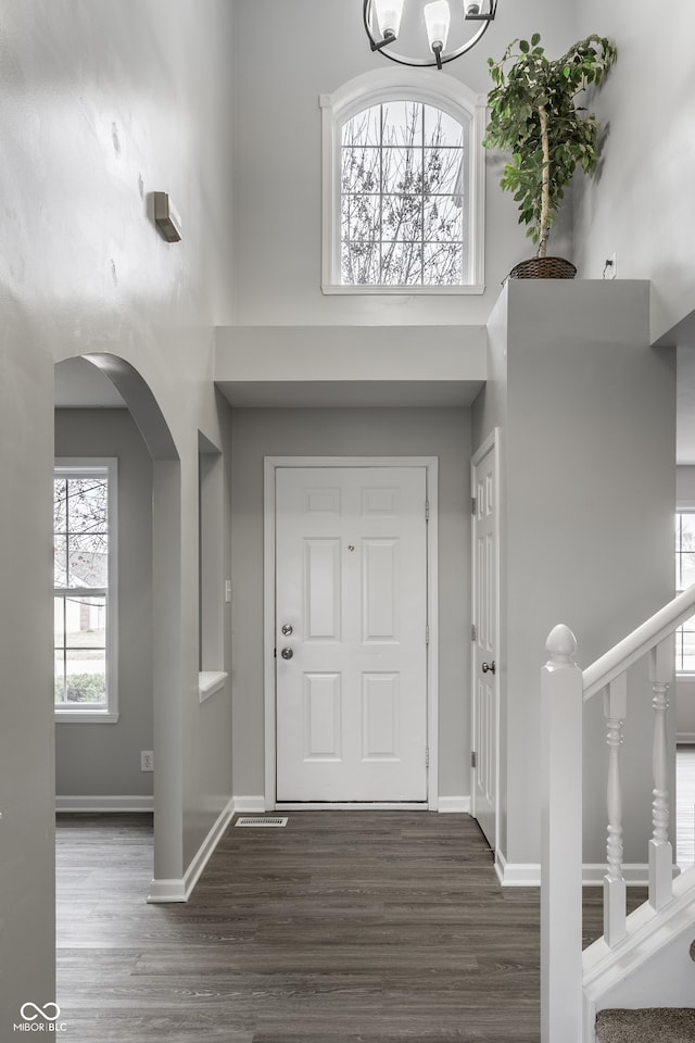 foyer entrance featuring a healthy amount of sunlight, dark wood-type flooring, and a high ceiling