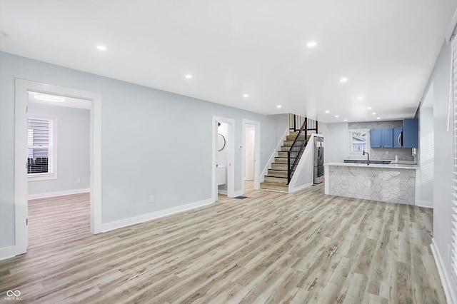 unfurnished living room featuring sink, light hardwood / wood-style flooring, and plenty of natural light