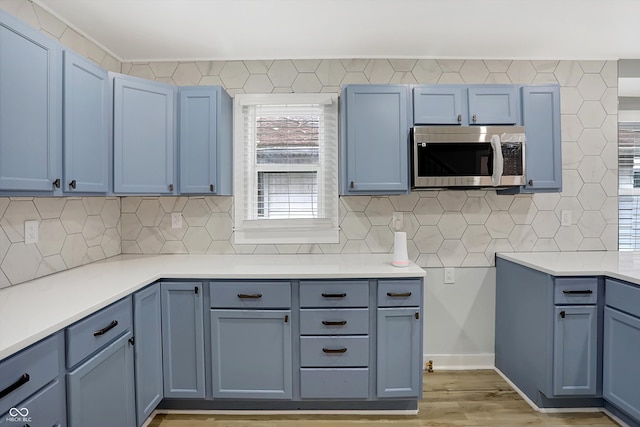 kitchen with light hardwood / wood-style floors, decorative backsplash, and blue cabinets