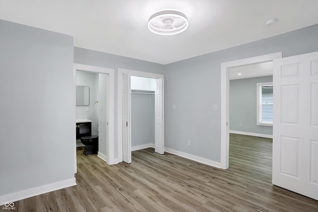 unfurnished bedroom with ensuite bath and light wood-type flooring